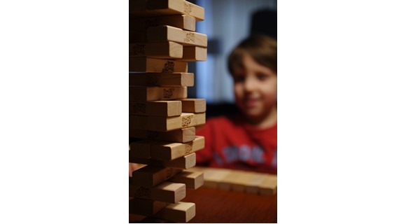 Jenga wooden block game with child in background 